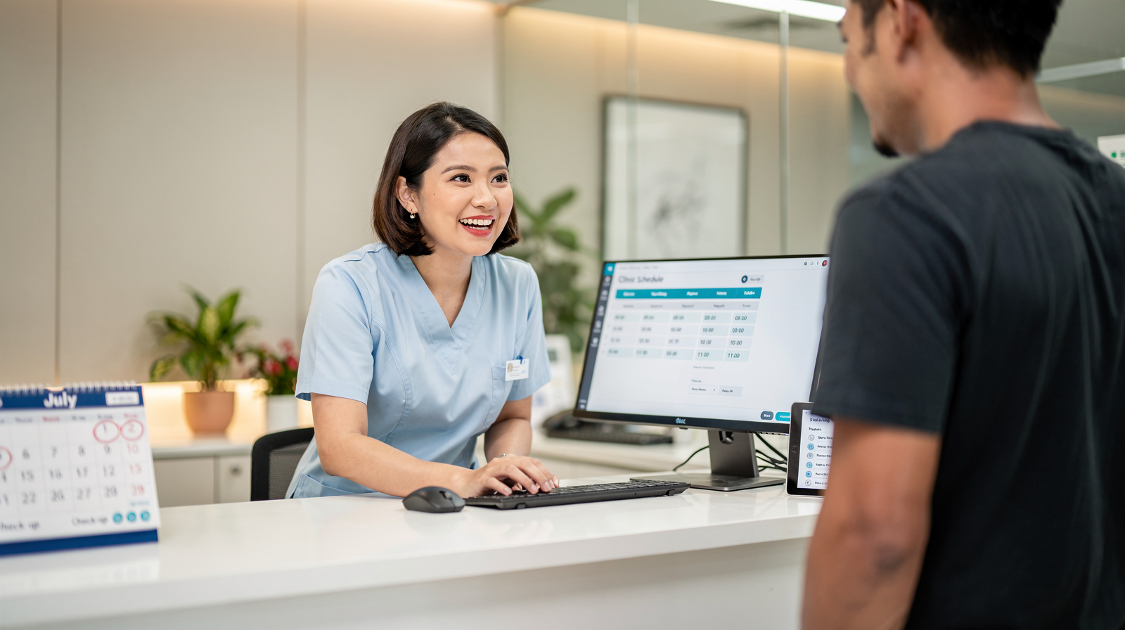 Friendly clinic receptionist smiling at reception desk with appointment scheduling workflow visible